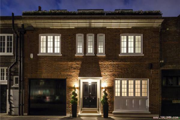 Khu nhà 4 tầng đắt giá có vẻ ngoài giản dị với mặt tiền để gạch mộc và những khung cửa trắng giống các khối nhà bên cạnh.
